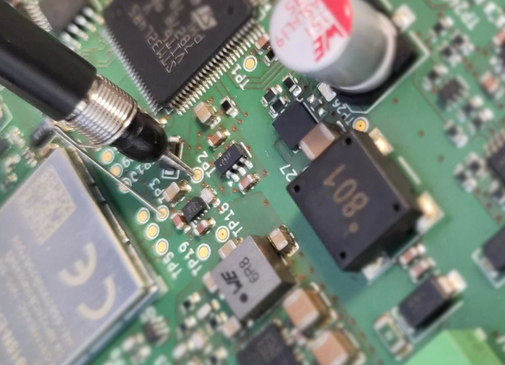 Close-up of test pads on the PCB with a scope probe attached